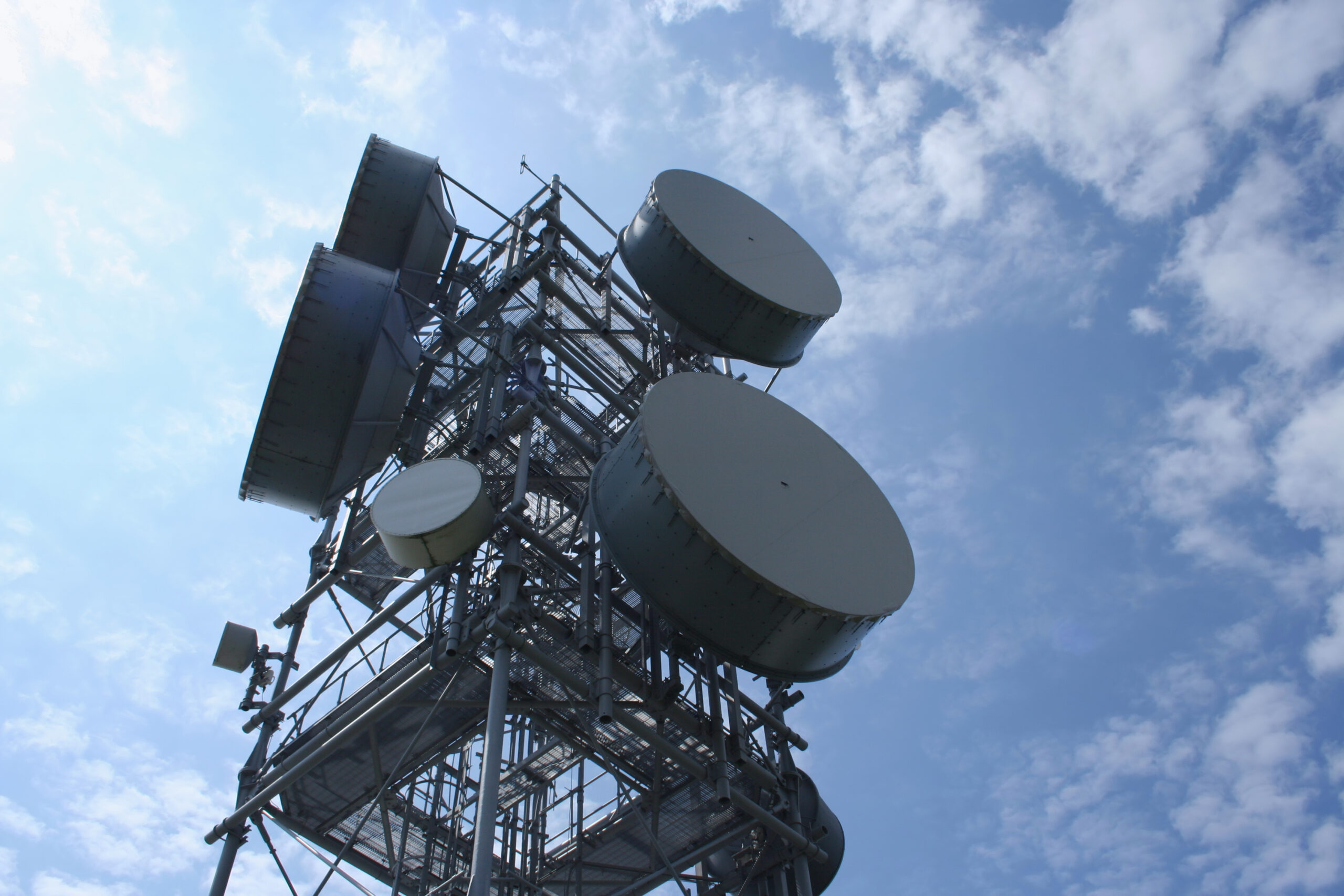 tower with microwave dishes Looking up at communication tower with numerous microwave dishes